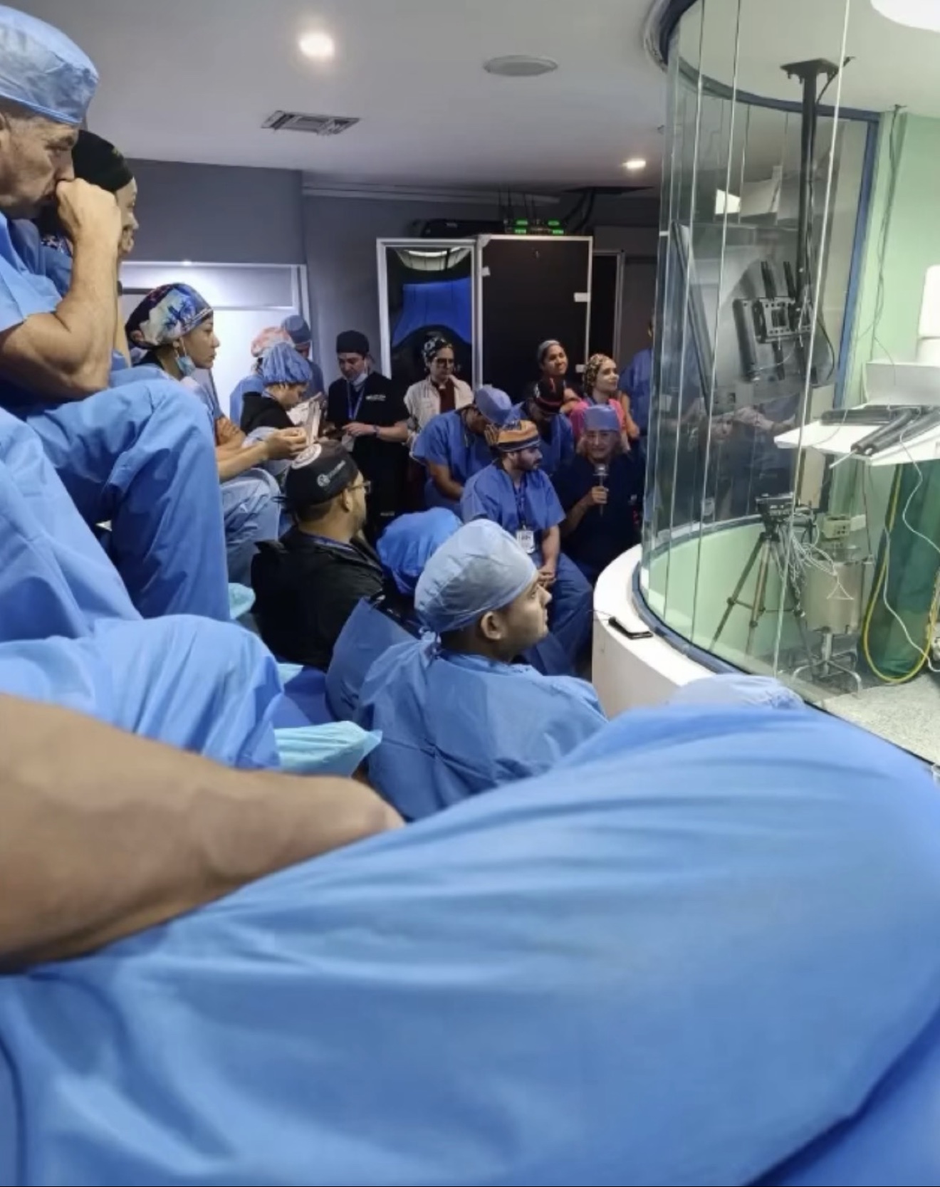 Sesión de entrenamiento en el IDU: médicos y residentes con uniforme quirúrgico observan un procedimiento en vivo a través del vidrio del quirófano — fotografía real del instituto
