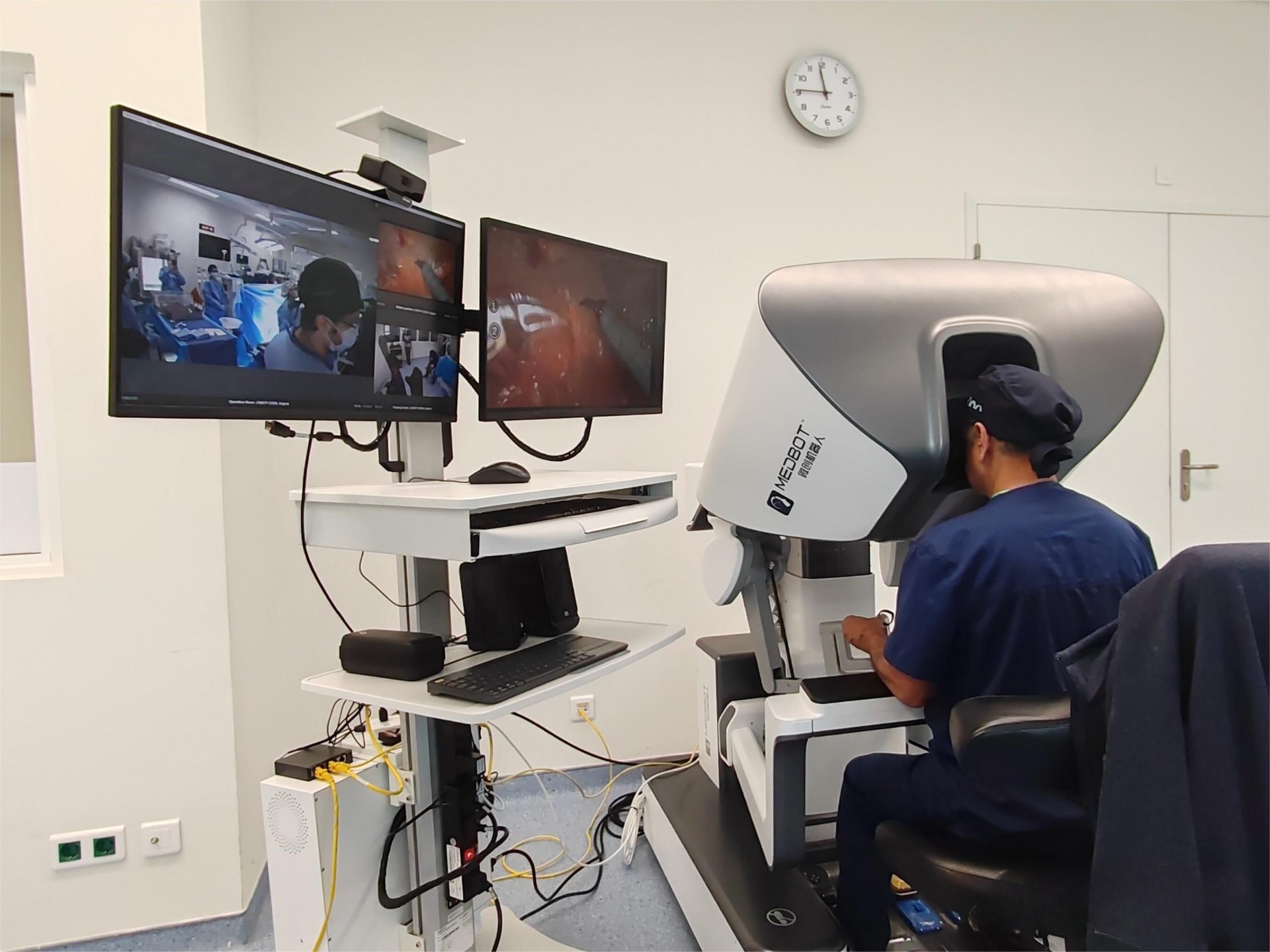 Cirujano operando el robot quirúrgico Toumai® de MicroPort MedBot desde la consola, con las pantallas de la cirugía en vivo — fotografía real del sistema